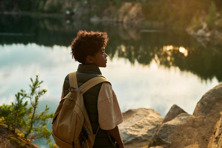 Rear view of African American boy with backpack enjoying the nature during hikingの写真素材