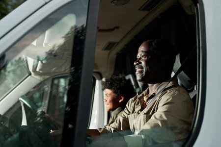 Happy African American Dad driving by van with his son