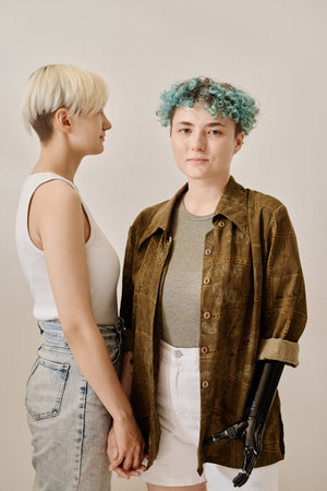 Vertical portrait of young lesbian couple posing at camera against white backgroundの写真素材