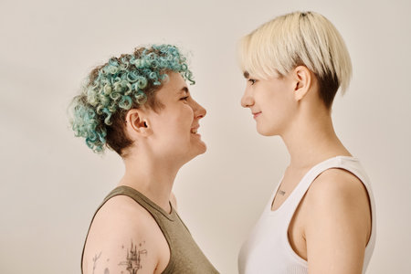 Portrait of happy lesbian couple looking at each other against white backgroundの写真素材