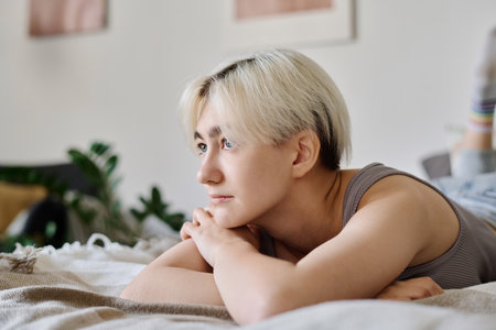 Young woman with short blond hair relaxing on her bed during her free time at homeの写真素材