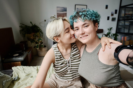 Happy lesbian girl making selfie portrait with her girlfriend in the roomの写真素材
