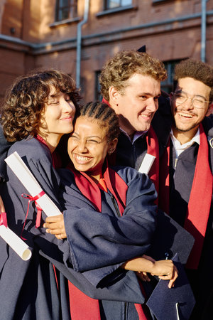 Vertical image of happy students embracing each other, they graduating from universityの写真素材