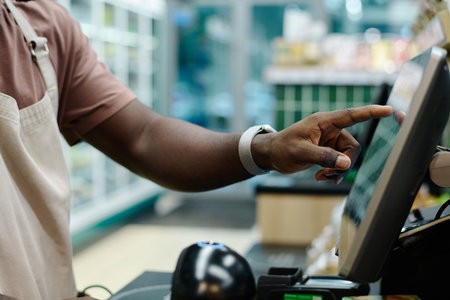 Close-up of cashier working on cash register in supermarket