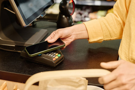 Close-up of customer paying for purchase online using her smartphoneの写真素材