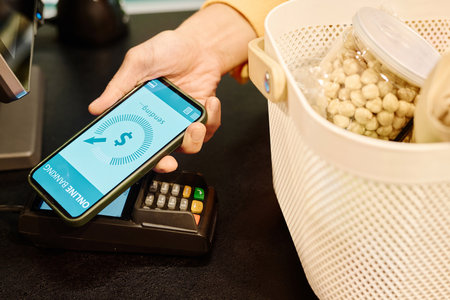 Close-up of customer using smartphone to pay for purchase in the store