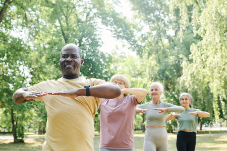 Group of senior people standing in a row and doing exercises during training outdoors in the morningの写真素材