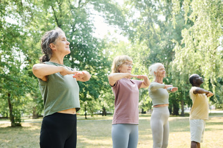 Group of senior people standing in a row and training outdoors in the parkの写真素材