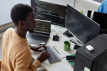 Serious African American developer working with security codes on computer at his workplace