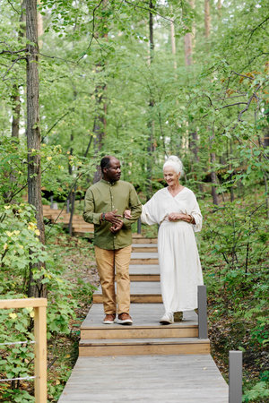 Vertical image of multiethnic senior couple walking in the forest togetherの写真素材