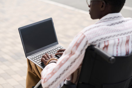Rear view of student using laptop for online study while spending time outdoorsの写真素材