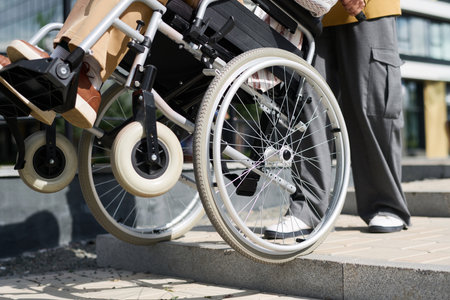 Close-up of man helping his friend with disability to go down the stairs outdoorsの写真素材