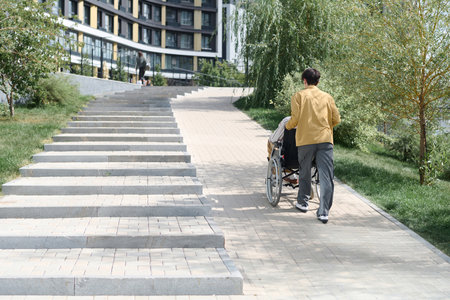 Rear view of young man walking with his friend with disability in the city