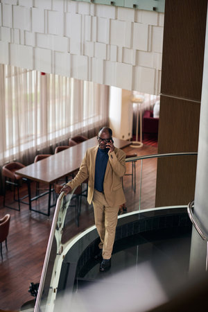 High angle view of African American businessman talking on the phone while standing on stairs in...