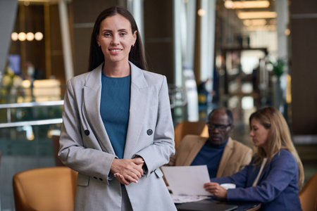 Portrait of businesswoman smiling at camera while having meeting with her colleagues in the hotel