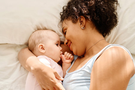 High angle view of mother lying with her baby on bed and enjoying the time togetherの写真素材