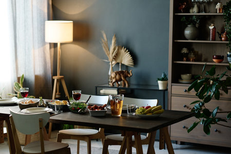 Part of spacious living room with table served with homemade food prepared for domestic festivity...