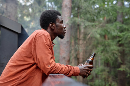 African American man drinking beer at picnic in the forest