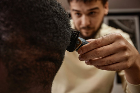 Barber using trimmer to shave the head of customer during his visit to barber shopの写真素材