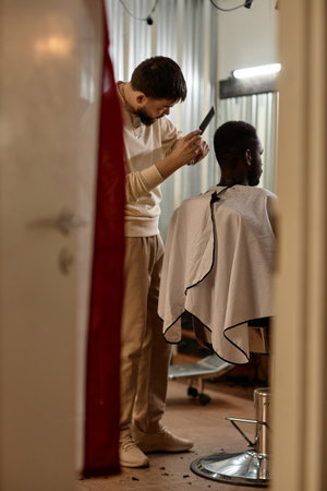 Vertical image of hairdresser doing haircut for customer in hair salonの写真素材