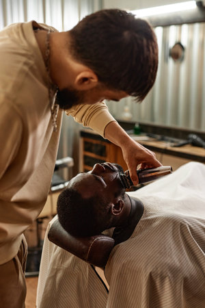 Barber using shaving machine to shave the customer in barber shopの写真素材