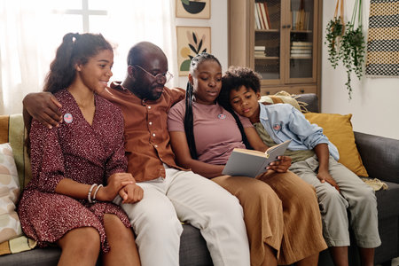 Hugging Black family sitting on couch and reading book about Martin Luther King Jr