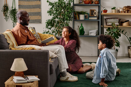 Cheerful son and daughter asking father to read book on African American history