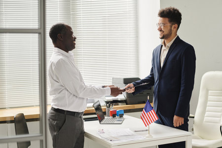 Happy African American man getting approved visa from specialist of visa centerの写真素材
