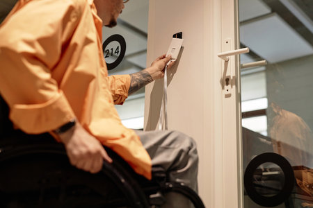Close-up of young man with disability opening door with electronic key in office corridorの写真素材