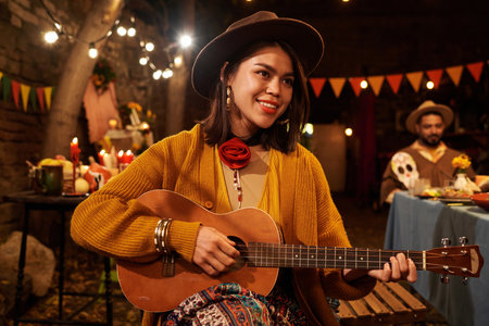 Young woman playing guitar during holiday at dinner party