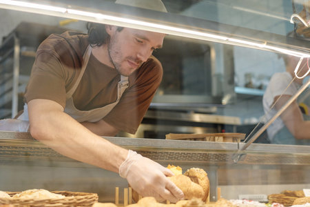 Cafe worker displaying pastry items in showcase for sale