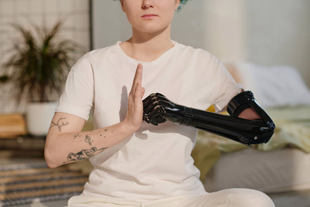 Cropped image of girl with cyber prosthetic arm making fist and palm gesture