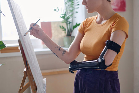 Cropped image of girl with prosthetic arm learning paintingの写真素材