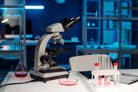 Laboratory workplace with microscope and glassware with liquid displayed on table