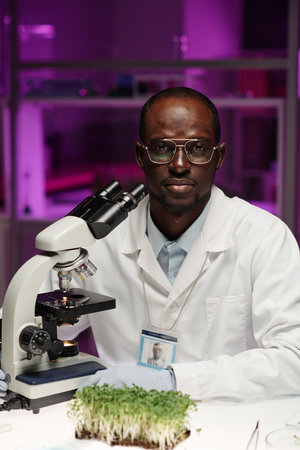 Medium shot of biologist confidently posing at his workplace in lab looking at cameraの写真素材