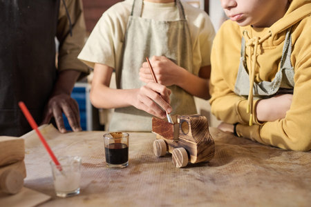 Close up of two children painting wooden toys model in carpenting workshop for kids, copy spaceの写真素材