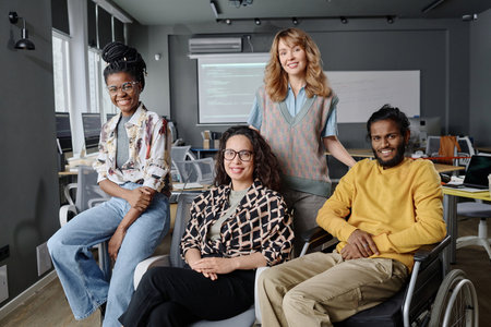 Diverse group of young coworkers posing together in office sitting and smiling at cameraの写真素材