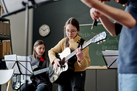 Selective focus shot of girl and her classmates playing instrumental music in classroom at schoolの写真素材