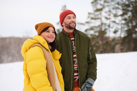Medium portrait of young Caucasian man and woman in love spending winter day hiking in mountains...