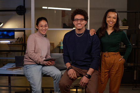 Portrait of three young ethnically diverse male and female programmers posing for camera in modern officeの写真素材