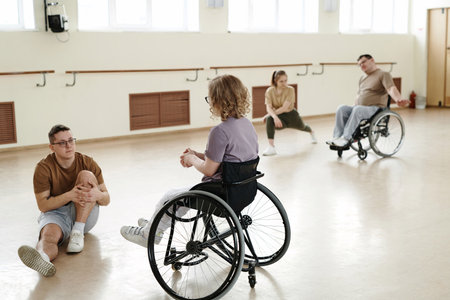 Selective focus shot of modern dancers with disabilities in wheelchairs and their partners doing warm-up exercisesの写真素材