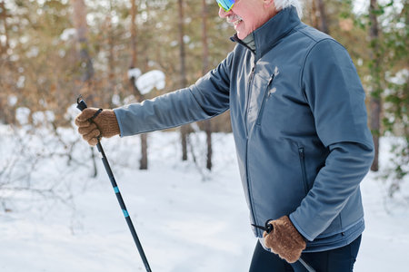 Side view crop shot of senior Caucasian man in sportswear skiing on winter day in park, copy spaceの写真素材