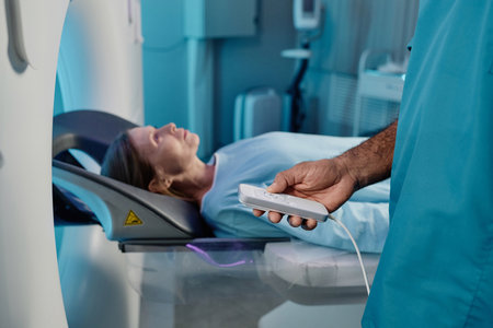 Unrecognizable radiographer holding controller turning on MRI scanner for mature Caucasian female...
