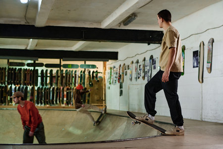 Group of active young men and woman riding bowl on skateboard in modern skatepark, copy spaceの写真素材