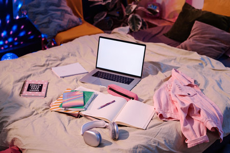 High angle view of laptop, headphones, textbooks and notebooks on bed in teenagers room interior, copy spaceの写真素材