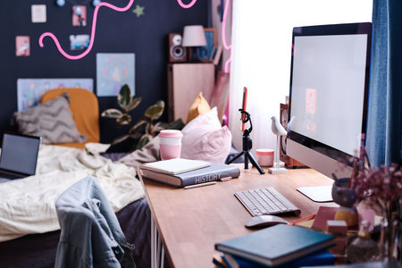 Selective focus shot of part of modern teen girls bedroom interior with computer on wooden desk, copy spaceの写真素材
