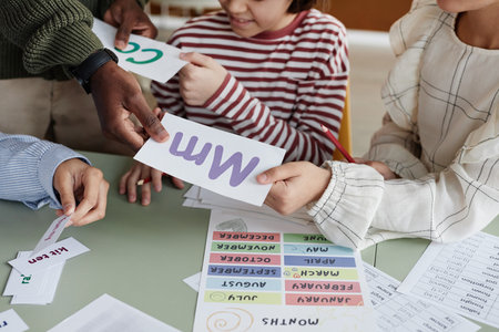 High angle view of unrecognizable foreign language teacher giving printouts to students during lessonの写真素材