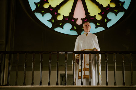 Wide shot of senior Caucasian Catholic priest wearing liturgical vestment standing at mezzanine in...