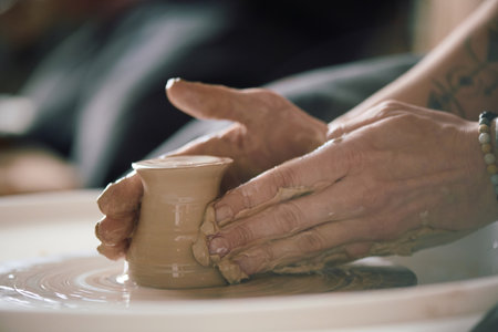 Closeup of hands of unrecognizable female artisan shaping clay on potters wheelの写真素材