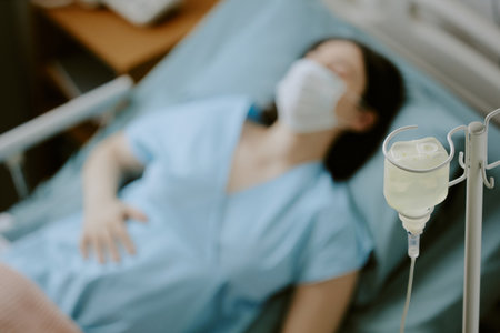 Medium close up of irrigation tubing set and pregnant woman lying on bed in backgroundの写真素材